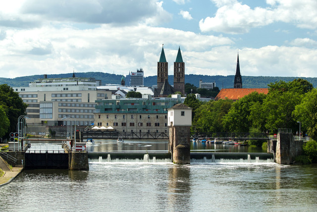 Staustufe mit Fußgängerbrücke vor der Kulisse einer nordhessischen Großstadt
