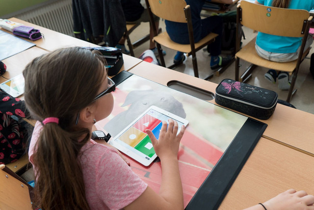 Schülerin sitzt am Tisch in Klassenzimmer einer Grundschule.