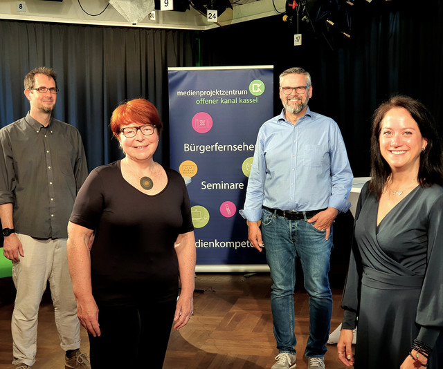 Podiumsgäste blicken in die Kamera.