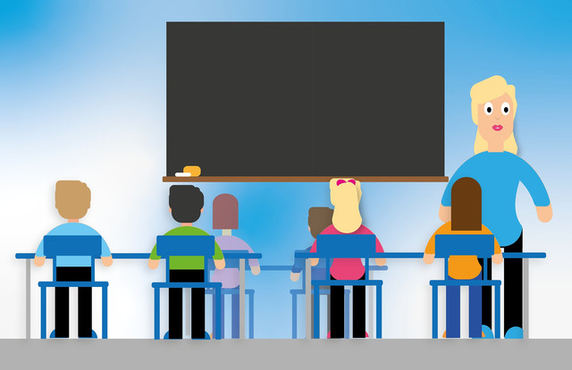 Kinder sitzen auf Stühlen an einzelnen Tischen und verfolgen den Unterricht. Im Hintergrund ist die Lehrerin neben einer großen Wandtafel zu sehen.