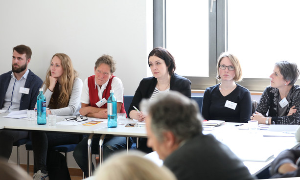 Zuhörende sitzen an U-förmig gestellten Tischen im Seminarraum 4.
